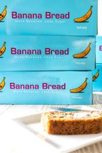 Boxes of Banana Bread with a slice on a plate in the foreground