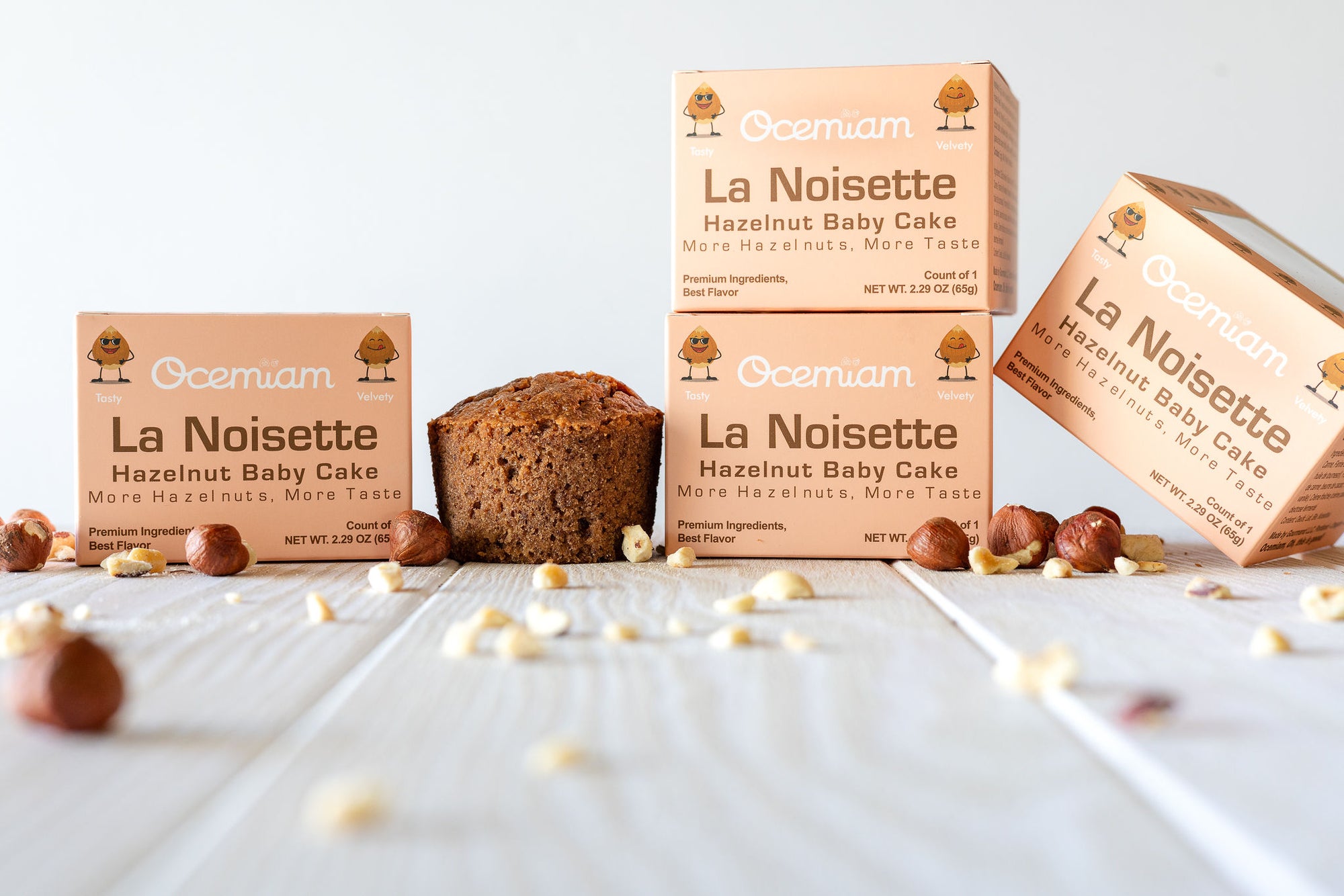 Ocemiam La Noisette Hazelnut Baby Cake boxes with a loaf of cake on a white surface.