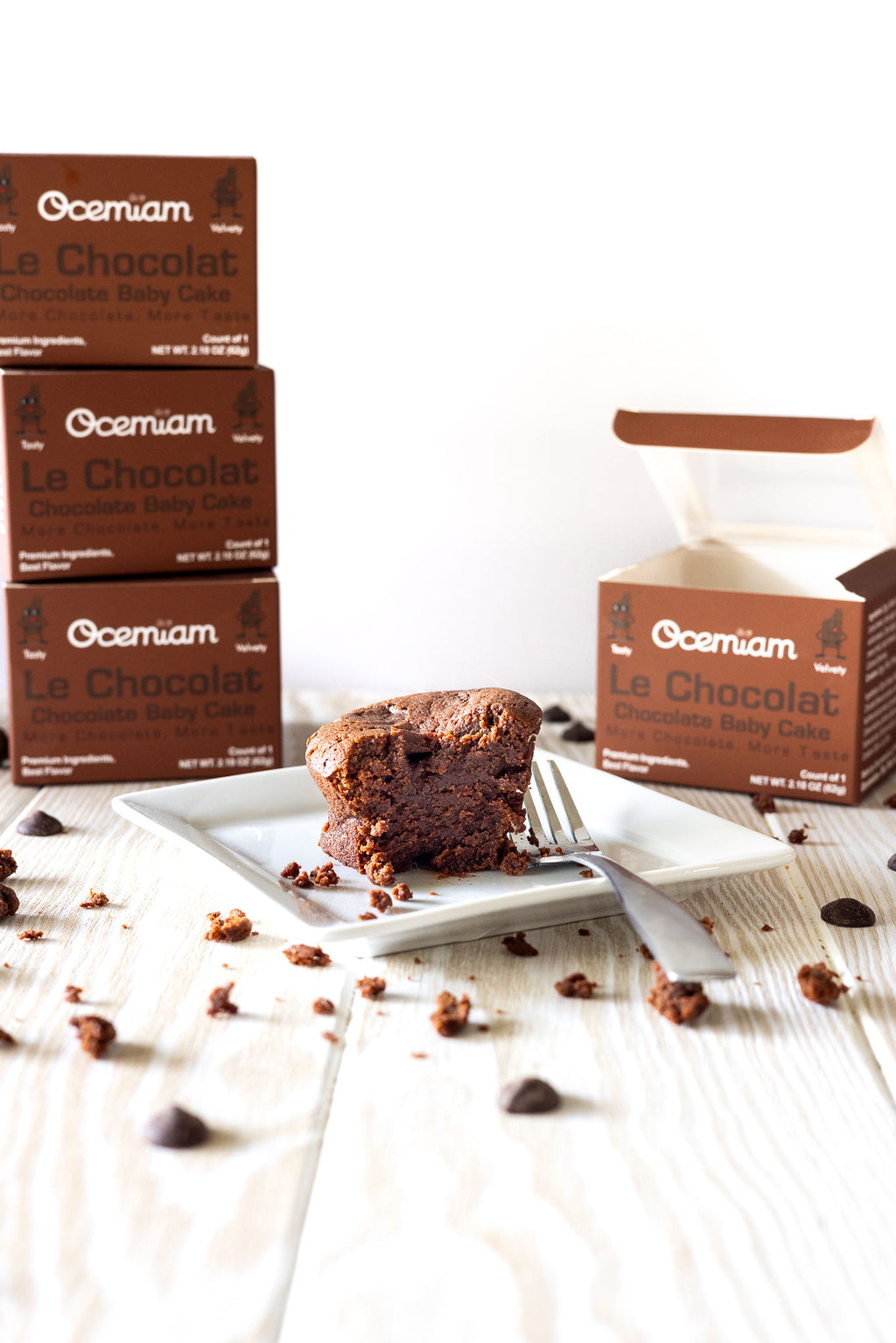 Chocolate cake on a plate with Ocemian Le Chocolat boxes in the background