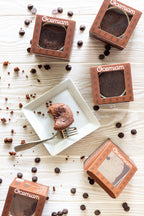 Chocolate cake slices in Ocemiam packaging on a wooden surface with scattered chocolate chips.